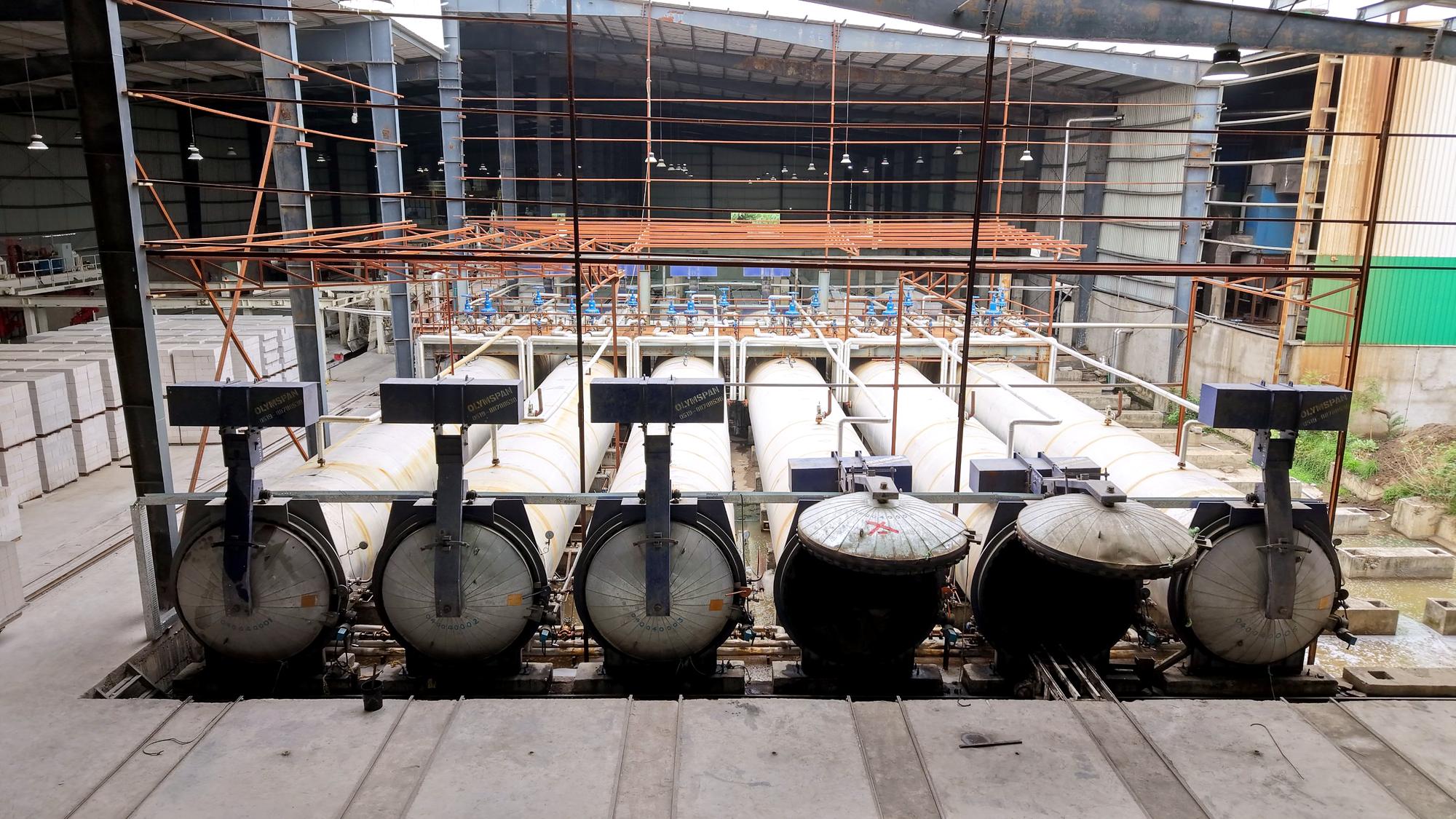 Six Olymspan autoclaves, two with their doors open, and finished AIWON blocks stacked on the left